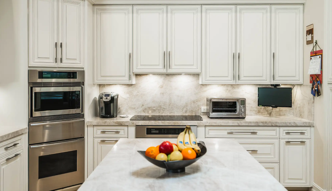 Creamy Taj Mahal Quartzite island and perimeter counters with classic white cabinetry.