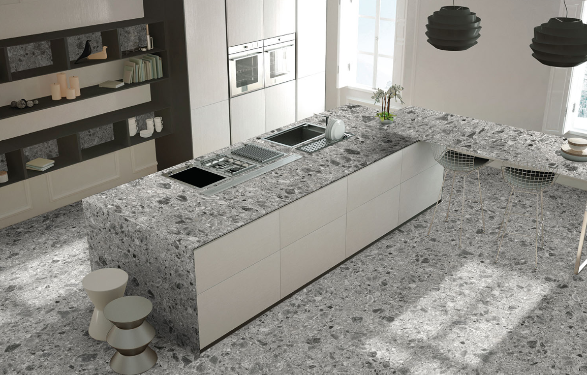 Relativa Ceppo Di Gre porcelain island and flooring with a grey pebbled, concrete-like aggregate pattern.
