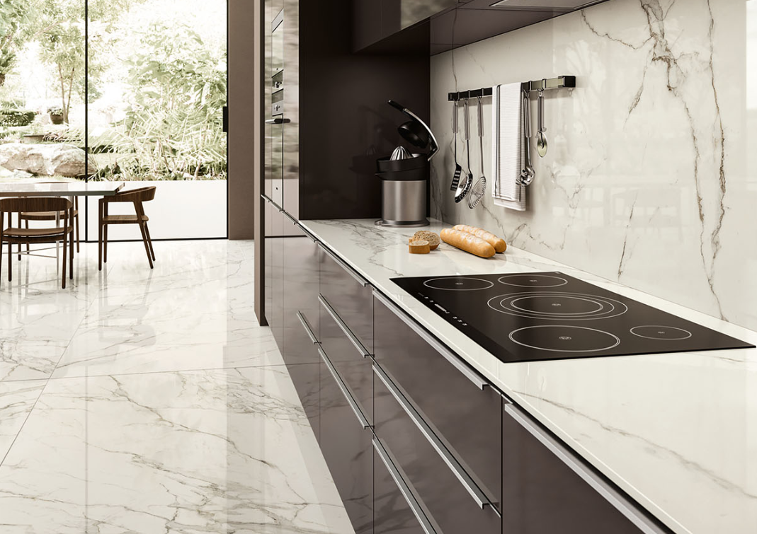 White marble-look Relativa Statuario Fantastico porcelain countertops and backsplash with glossy dark cabinetry.